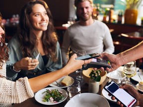 Friends paying contactlessly in restaurant