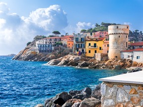 The tiny seaside village of “Giglio Porto” with multi-coloured houses, an ancient defensive tower and a rocky coastline against a deep blue Mediterranean sea on Giglio Island. GETTY