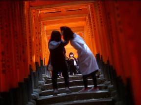 Visitors wearing masks explore the wooden torii gates at Fushimi Inari Taisha shinto shrine in Kyoto, Japan March 13, 2020.