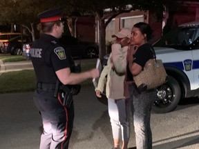 A Peel police officers speaks to people near the scene of a fatal shooting in Mississauga on Wednesday, June 22, 2022.