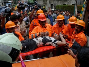 A boy grimaces as rescue workers carry him after he was rescued from the rubble at the site of a collapsed residential building in Mumbai, India, June 28, 2022.