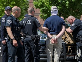 A police officer holds one of a group of men, among 31 arrested for conspiracy to riot and affiliated with the white nationalist group Patriot Front, after they were found in the rear of a U-Haul van in the vicinity of a North Idaho Pride Alliance LGBTQ+ event in Coeur d'Alene, Idaho, Saturday, June 11, 2022.