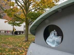 A disposed medical mask is seen stuffed in a garbage bin in Toronto, Monday, Oct. 19, 2020.
