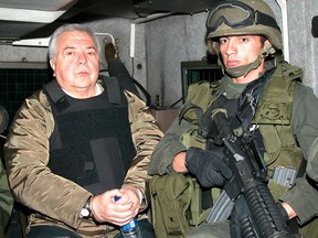 The former boss of the powerful Cali drug cartel, Gilberto Rodriguez Orejuela is escorted by a Colombian policeman before being extradited to the United States in Bogota, Colombia, December 3, 2004.
