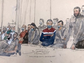 In this file photo taken on June 27, 2022 This court-sketch made on June 27, 2022, shows defendant Salah Abdeslam, right, standing next to the 13 other defendants in front of Paris' criminal court during the trial of the November 2015 attacks.