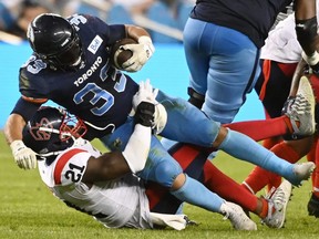 Toronto Argonauts running back Andrew Harris (33) is tackled by Montreal Alouettes linebacker Chris Ackie (21) during first second CFL football action in Toronto on June 16, 2022.