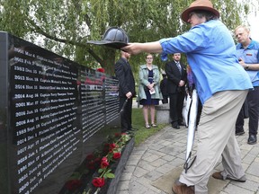 Joanne Skene lays the hard leather helmet her father Robert Chalmers wore in the 1960s atop a section of the "Last Alarm" memorial on Sunday, June 12, 2022. Chalmers died on Nov. 4, 2020 as a line-of-duty death related to cancer. He served from 1962 to 1989. Twenty one new names were added to Toronto Fallen Firefighter Memorial down at the "Last Alarm" monument.
