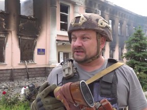 Ein Polizeibeamter spricht, während er den Schaden durch Artillerie der russischen Armee begutachtet, mit einem schwer beschädigten zivil-militärischen Verwaltungsgebäude der Stadt im Hintergrund, in Lysychansk, Ukraine, 5. Juni 2022 in diesem Standbild aus Handout-Video.