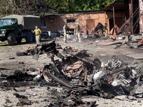 Soldaten untersuchen Schäden und Bergungsgegenstände, nachdem ein Projektil und ein anschließender Brand am Vorabend des 21. Juni 2022 in Druzhkivka, Ukraine, ein Lagergebäude zerstört hatten.
