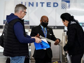 A United Airlines worker assists travelers after the Biden administration announced it would no longer enforce a U.S. COVID-19 mask mandate on public transportation at Ronald Reagan Washington National Airport in Arlington, Virginia April 19, 2022.