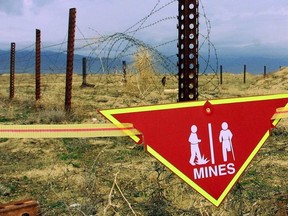 An international sign warning about mines hangs beside a minefield at Bagram Air Base on, March 22, 2002.