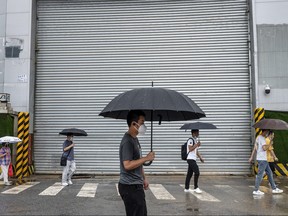 People walk along a street during a rainy morning rush hour on June 29, 2022 in Beijing.