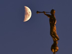 The waxing crescent moon at 41% exposed, starts to rise behind a golden statue as the sun starts to set in west Edmonton, November 10, 2021.