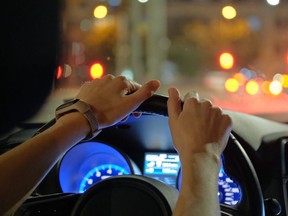 Close up of a motorist holding the steering wheel while driving a car.