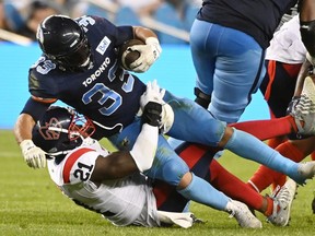 Toronto Argonauts running back Andrew Harris (33) is tackled by Montreal Alouettes linebacker Chris Ackie (21) during first second CFL football action in Toronto Thursday, June 16, 2022.