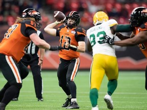 B.C. Lions quarterback Nathan Rourke (12) passes as Phillip Norman (50) holds off Edmonton Elks' Kwaku Boateng (93) during the first half of a CFL football game in Vancouver, on Friday, November 19, 2021.