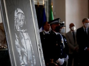 A mural by anonymous British street artist Banksy stolen from the Bataclan theatre in Paris and found in a farmhouse in central Italy is seen during the ceremony to return to France at the French embassy in Rome, Italy. July 14, 2020.