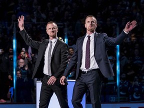 Vancouver Canucks former players Daniel Sedin and Henrik Sedin of Sweden react during a number retirement ceremony held prior to a game between the Vancouver Canucks and Chicago Blackhawks at Rogers Arena.