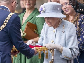 Queen Elizabeth inspects the keys presented by Lord Provost Robert Aldridge, left, during the Ceremony of the Keys on the forecourt of the Palace of Holyroodhouse in Edinburgh Monday, June 27, 2022.