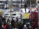 Ein Demonstrant steht auf seinem Fahrzeug, um Polizisten von Surete du Quebec zuzusehen, wie sie Fahrzeuge in einer Blockade in der Rideau Street umzingeln, um einen Protest gegen COVID-19-Maßnahmen zu beenden, der sich zu einem breiteren Protest gegen die Regierung entwickelt hat Ottawa, 18. Februar 2022.