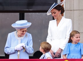 Königin Elizabeth II. spricht mit Prinz Louis von Cambridge, während Catherine, Herzogin von Cambridge und Prinzessin Charlotte von Cambridge während der Trooping the Colour-Parade am 2. Juni 2022 in London auf den Balkon des Buckingham Palace blicken.