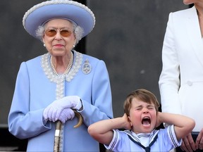Prince Louis of Cambridge holds his ears as he stands next to Queen Elizabeth II to watch a special flypast from Buckingham Palace balcony following the Queen's Birthday Parade, the Trooping the Colour, as part of Queen Elizabeth II's platinum jubilee celebrations, in London on June 2, 2022.