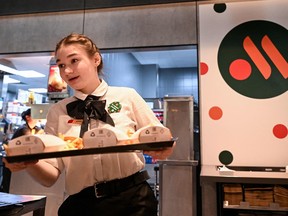 An employee holds a food order on a tray in the Russian version of a former McDonald's restaurant after the opening ceremony in Moscow on June 12, 2022.