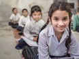 This file photo shows a girl sitting on the floor of her government primary school in uniform along with some of her class mates sitting behind her.