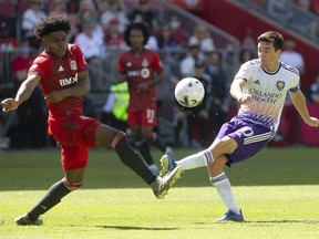 Orlando City's Mauricio Pereyra (right) has his shot blocked by Toronto FC's Ralph Priso during first half MLS action in Toronto, Saturday, May 14, 2022. Major League Soccer has signed a 10-year deal with Apple that will give the tech giant broadcast rights for every MLS match beginning in 2023.
