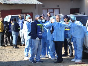 Police and investigators put on protective clothing before going into a township pub in South Africa's southern city of East London on June 26, 2022.