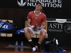 Denis Shapovalov of Canada holds his shoes during reacts as he sits on the bench during his match against Casper Ruud of Norway at the Italian Open tennis tournament, in Rome, Friday, May 13, 2022.