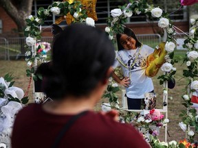 A woman walks by a photo cutout of Amerie Jo Garza, one of the victims of the Robb Elementary school mass shooting that resulted in the deaths of 19 children and two teachers, at the school memorial site on the day of her funeral in Uvalde, Texas, U.S., May 31, 2022.