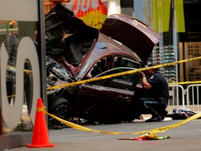 A police officer tries to take pictures of the scene as other police officers secure the area near a car after it plunged into pedestrians in Times Square in New York on May 18, 2017.