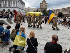 Members of the Honour Guard carry a coffin with the body of Roman Ratyshnyi, a Ukrainian public activist and service member, who was recently killed in a battle against Russian troops, at the Independence Square in Kyiv, Ukraine June 18, 2022.