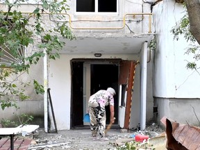 A woman sweeps outside an apartment building after deadly rocket strikes at a residential area of Mykolaiv, amid Russia's attack on Ukraine, in this still image from undated handout video released June 17, 2022.