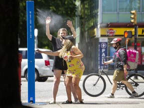 Carter and Amber cool off at a misting station on Commercial Drive in Vancouver, June 26, 2022.