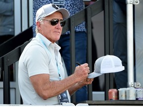 LIV Golf commissioner Greg Norman signs hats from the deck of a pavilion on the 18th green during the final round of the LIV Golf Invitational - Portland at Pumpkin Ridge Golf Club on July 02, 2022 in North Plains, Oregon.