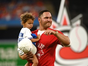 Former Toronto Blue Jays catcher Russell Martin with one of his daughters watches a video display of his time with the team after announcing his retirement from professional baseball before the game between the Blue Jays and the Tampa Bay Rays in Toronto on Friday, July 1, 2022.