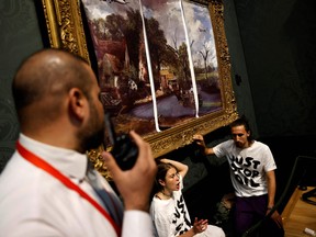 Activists from the 'Just Stop Oil' campaign group, with hands glued to the frame of the painting 'The Hay Wain' by English artist John Constable, but covered in a mock 'undated' version including roads and aircraft, protest against the use of fossil fuels, in the National Gallery in London on July 4, 2022.