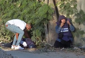 In this file image grab from footage distributed by the Doha-based Al-Jazeera TV shows a reporter reacting (R) as an unidentified man tries to lift the body of the channel’s veteran journalist Shireen Abu Aqleh (Akleh) from the ground after she was fatally wounded by gunfire in Jenin in the occupied West Bank on May 11, 2022. (Photo by AL JAZEERA/AFP via Getty Images)