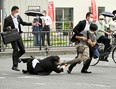 This image received from the Asahi Shimbun newspaper shows a man (centre R) suspected of shooting former Japanese prime minister Shinzo Abe being tackled to the ground by police at Yamato Saidaiji Station in the city of Nara on July 8, 2022. - Abe was pronounced dead on July 8, the hospital treating him confirmed, after he was shot at a campaign event in the city of Nara.