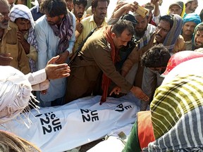 Rescue workers and local villagers gather around the bodies of drowned victims after an overcrowded boat carrying a Pakistan wedding party capsized on the outskirt of Sadiqabad town on July 18, 2022.
