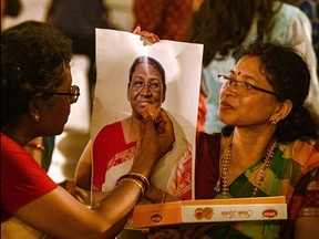 The Bharatiya Janata Party (BJP) worker touches sweets to a picture of India's President elect Droupadi Murmu at her temporary residence after she was elected as country's new president in New Delhi on July 21, 2022.