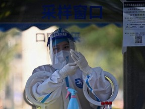 A health worker is seen at a swab collection booth for COVID-19 in Beijing, Wednesday, July 6, 2022.