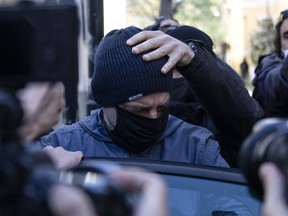Plain-clothed policemen escort actor-director Dimitris Lignadis gets into a police car as he leaves a magistrate's office in Athens, Wednesday, Feb. 24, 2021.