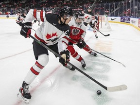 Canada's Kaiden Guhle (21) and Austria's Marco Kasper (19) battle for the puck during first period IIHF World Junior Hockey Championship action in Edmonton on Tuesday, December 28, 2021.