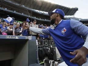 Toronto Blue Jays' Teoscar Hernandez tosses a ball cap back to a fan as he signs autographs before the team's baseball game against the Seattle Mariners, Saturday, Aug. 4, 2018, in Seattle.