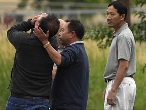 A man cries out as he is overcome with emotion while teams in dry suits and Ramsey County Sheriff's deputies search for the bodies of a mother and her three children at Vadnais Lake, Saturday, July 2, 2022, in Vadnais Heights, Minn.