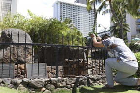 Kekoa Hager presents an offering at the Kapaemahu stones at Waikiki beach in Honolulu. A new exhibit at Honolulu’s Bishop Museum draws attention to the stones which honour four “mahu” healers from Tahiti who visited Hawaii more than five centuries ago. (AP Photo/Audrey McAvoy)