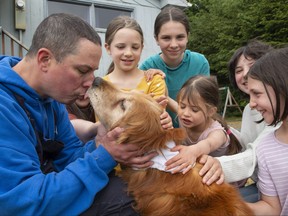 Ted Kubacki gets licked by the family's golden retriever, Lulu, outside their home after being reunited in Sitka, Alaska on Thursday, July 7, 2022. The elderly, blind dog who had been missing for three weeks was found on Tuesday July the 5th. , 2022, by a construction crew in salmonberry bushes after initially mistaking her for a bear. Behind Ted are his wife, Rebecca, and their children Ella, Viola, Star, Lazaria and Olive.